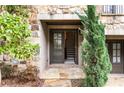 Charming townhome entrance features a stone facade, double doors, and lush greenery, creating an inviting entryway at 6657 Encore Blvd, Atlanta, GA 30328