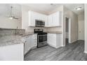 Well-lit kitchen with white cabinets, stainless steel appliances, granite countertops, and a view into the next room at 503 Goldfinch Way, Stockbridge, GA 30281