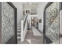 Elegant foyer featuring a modern staircase, decorative doors, and light gray wood-look flooring at 2755 Turning Leaf Dr, Lawrenceville, GA 30044