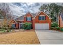 Classic red brick home with a two-car garage and well-maintained lawn at 9235 Heatherton Walk, Duluth, GA 30097