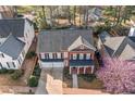 An aerial view of a neighborhood showcasing a traditional two-story brick home with well-maintained landscaping at 1545 Heritage Trl, Roswell, GA 30075