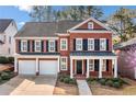 Beautiful red brick two-story home featuring a covered porch, black shutters, and an attached two-car garage at 1545 Heritage Trl, Roswell, GA 30075