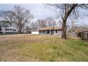 Single-story home with gray brick, attached garage, green lawn and mature shade trees on a bright, sunny day at 6451 Katherine St, Douglasville, GA 30134