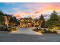 Elegant home exterior with beautiful landscaping, circular driveway, and stone accents at dusk at 2805 Cambria Ct, Cumming, GA 30041