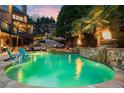 Beautiful pool with a stone waterfall, palm trees, and a fire feature, creating a serene outdoor oasis at 2805 Cambria Ct, Cumming, GA 30041