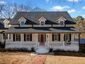 Beautiful home featuring a covered porch, black shutters, red door, and a brick walkway at H-5422 Hill Sw Rd, Powder Springs, GA 30127