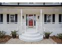 Inviting front porch with red door, stylish sconces, and brick steps at H-5422 Hill Sw Rd, Powder Springs, GA 30127
