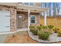 Inviting front porch showcasing stone detailing, white columns, and neatly landscaped garden beds at 114 Green Tree Ct, Dacula, GA 30019