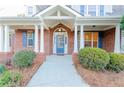 Inviting front porch with brick facade, white columns, blue door and shutters, and manicured shrubs at 2474 Starfire Ln, Loganville, GA 30052