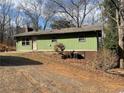 Exterior view of a home with green siding, a compact yard, and a gravel driveway at 420 Lee Dr, Acworth, GA 30102