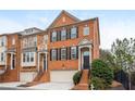 Exterior elevation of a three-story brick townhome featuring attached garage and professionally landscaped yard at 2826 Loftview Sq # 4, Atlanta, GA 30339