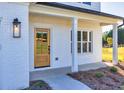 Close-up of a home's entry with white painted brick, wood door, and traditional lantern-style fixture at 3555 New Hope Rd, Dacula, GA 30019