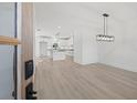 Open-concept dining area and kitchen with wood flooring, white cabinetry, and modern lighting fixtures at 3563 New Hope Rd, Dacula, GA 30019