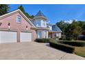 Brick home with a two-car garage and a long, curved driveway framed with hedges at 190 Winford Close, Duluth, GA 30097