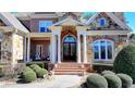 A stunning home showcasing a brick and stone exterior, arched doorway, and meticulously maintained landscaping at 2892 Darlington Run, Duluth, GA 30097