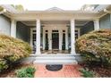 Inviting front porch with brick detail and stone tile, framed by elegant columns and lush greenery at 3045 Camp Branch Rd, Buford, GA 30519