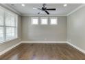 Well-lit living room features hardwood floors, a ceiling fan, and three windows at 607 Leland Pkwy, Cumming, GA 30041