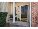 Inviting front porch featuring a black front door, brick accents, and decorative plants and chair at 2939 Greyhawk Ln, Cumming, GA 30040