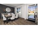 Formal dining room features wainscoting, a large window, modern lighting, and sleek hardwood floors at 218 Highgrove Way, Dallas, GA 30157