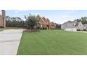 Well-manicured lawn leads up to a red brick two-story house with green shutters and a driveway at 50 Cannonade Ct, Covington, GA 30016