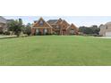 Well-manicured lawn leads up to a red brick two-story house with green shutters and a driveway at 50 Cannonade Ct, Covington, GA 30016