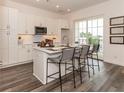 Bright kitchen with white cabinets, stainless steel appliances, and an island with barstool seating near a sliding glass door at 542 Sawnee Village Blvd # D69, Cumming, GA 30040