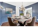 Blue dining room with modern chandelier, wainscoting, and a large square table at 160 Deer Cliff Cv, Lawrenceville, GA 30043