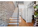 Bright foyer featuring a wooden staircase with a brick accent wall and hardwood flooring at 1605 Ridenour Nw Pkwy, Kennesaw, GA 30152