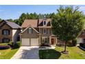 Two-story home featuring a well-maintained lawn, a two-car garage, and a beautiful tree in the front yard at 730 Pear Grove Pl, Marietta, GA 30066