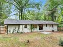 Back exterior of home showing white painted brick, mature vines, and fenced yard at 5626 Noblett Sw Rd, Stone Mountain, GA 30087