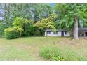 Cozy single-story home with white paint, black trim, and mature trees in a lush front yard at 5626 Noblett Sw Rd, Stone Mountain, GA 30087