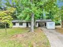 Charming single-story home with white paint, black trim, and mature shade trees in a lush yard at 5626 Noblett Sw Rd, Stone Mountain, GA 30087