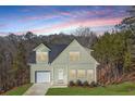 Charming two-story home with a light green exterior and a neatly attached single-car garage, with a lush lawn at 3185 Tackett Rd, Douglasville, GA 30135