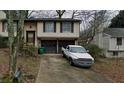 Two-story home with a two-car garage, driveway, neutral siding, and dark shutters on a wooded lot at 4233 Village Square Ln, Stone Mountain, GA 30083