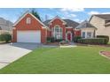 Charming red brick home featuring an attached two-car garage and a well-manicured green front lawn at 4198 Haynes Mill Nw Ct, Kennesaw, GA 30144