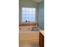 Bathroom featuring tub with tile surround and a frosted window for natural light and privacy at 4728 Sedum Way, Atlanta, GA 30349