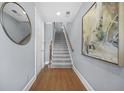 Hallway with hardwood floors, gray walls, staircase, decorative mirror, and modern art at 2102 Monhegan Se Way # 2102, Smyrna, GA 30080