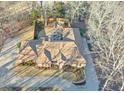 Overhead view of a brick home featuring a large, landscaped yard, patio, and surrounding trees at 8720 Rhapsody Ln, Cumming, GA 30041