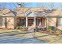 Charming brick home featuring a well-manicured front lawn, walkway, and a welcoming front porch at 8720 Rhapsody Ln, Cumming, GA 30041