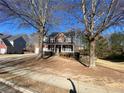 Traditional two-story brick home with a covered front porch and mature trees in a residential neighborhood at 2124 Mitford Ct, Dacula, GA 30019