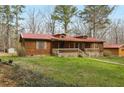 Charming single-story home featuring wood siding, a red metal roof, and a cozy front porch at 4009 Highway 138 Sw, Stockbridge, GA 30281