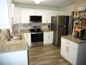 Modern kitchen features stainless steel appliances, white cabinetry, granite counters, and stylish wood floors at 4678 Browns Mill Ferry Rd, Lithonia, GA 30038