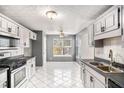 Well-lit kitchen with white cabinets, stainless steel appliances, and tile floors at 2733 Cedar Tree Ln, Ellenwood, GA 30294