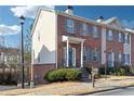 A view of a brick townhome with blue shutters, a covered entry, and mature bushes at 5968 Eagle Tiff Ln, Sugar Hill, GA 30518