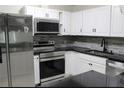 Modern kitchen equipped with stainless steel appliances, sleek black countertops, and white cabinets at 6658 Collins Ct, Riverdale, GA 30274