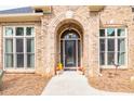 Elegant front door with arched entryway, flanked by large windows and mature landscaping at 2915 Pruitt Rd, Cumming, GA 30041
