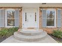 Home entrance with gray shutters, brick facade, updated windows and freshly painted white door at 4755 Huntley Dr, Atlanta, GA 30342