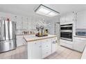 Bright kitchen with stainless steel refrigerator, white cabinetry, and a center island for food preparation and storage at 1165 Saint Ives Ct, Suwanee, GA 30024