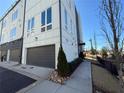 Contemporary townhouse featuring a gray garage door, sidewalk, and manicured shrubbery at 827 Winslow Nw Way, Atlanta, GA 30318