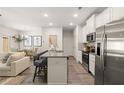 Open-concept kitchen has white cabinetry, a kitchen island, stainless steel appliances, and modern lighting at 549 Tuskegee St, Mcdonough, GA 30253